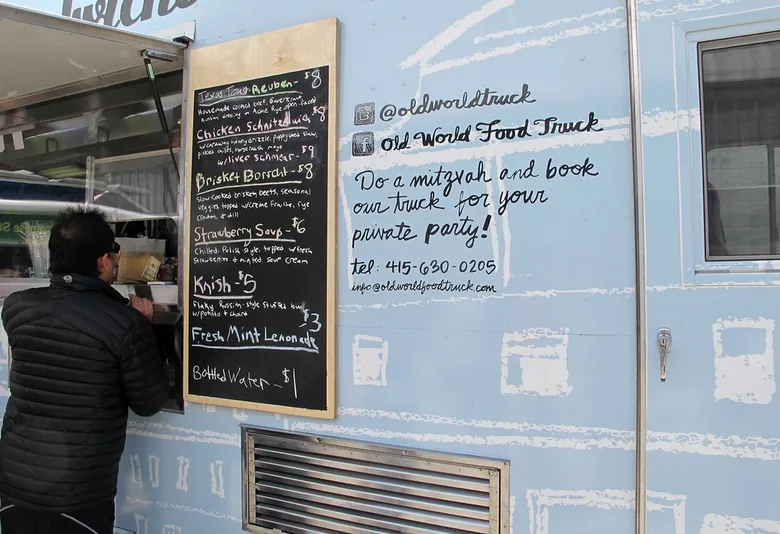 Food truck chalkboard menu mounted outside a blue street food van